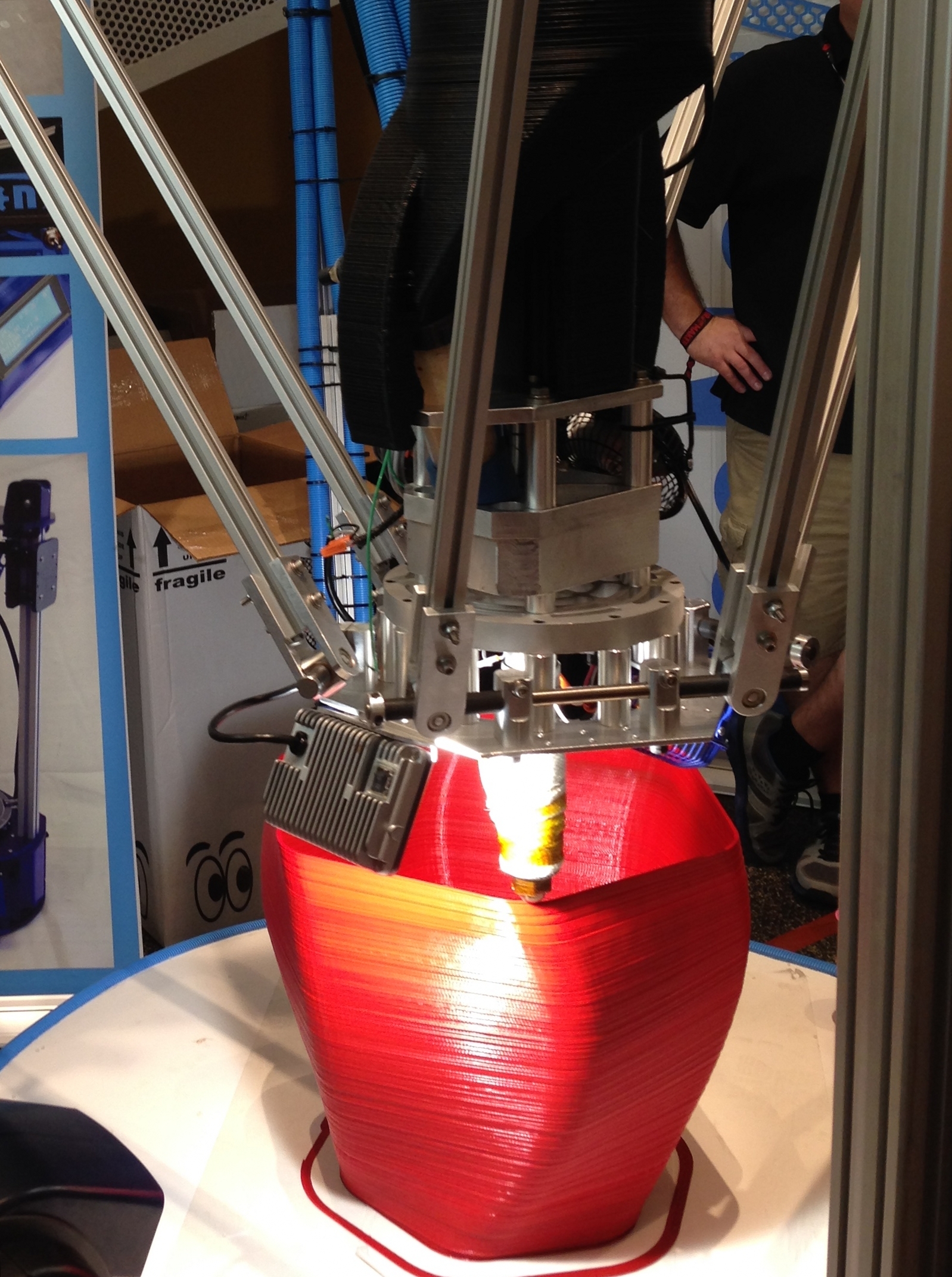 A tall delta-style printer framed against a workshop wall