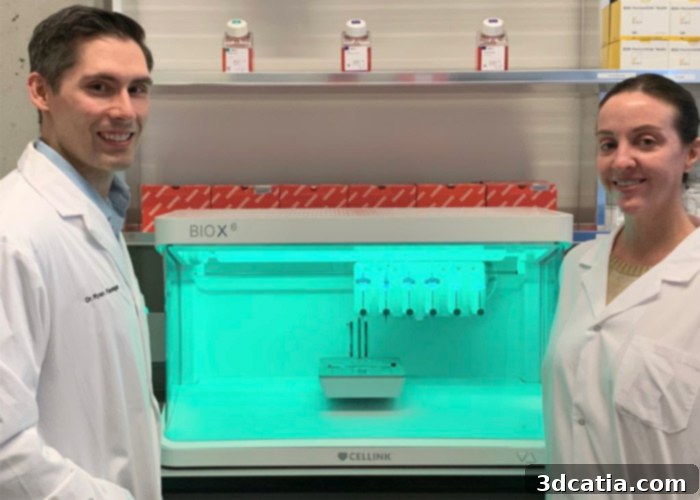 Dr. Flannigan and assistant Meghan Robinson in front of a 3D bioprinter at UBC, indicating scientific research.