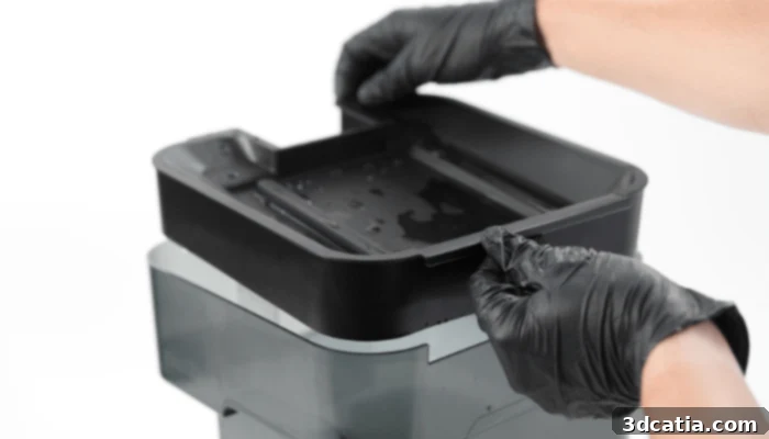 A technician carefully replacing the solvent in a wash station for resin 3D printed parts, highlighting proper maintenance.
